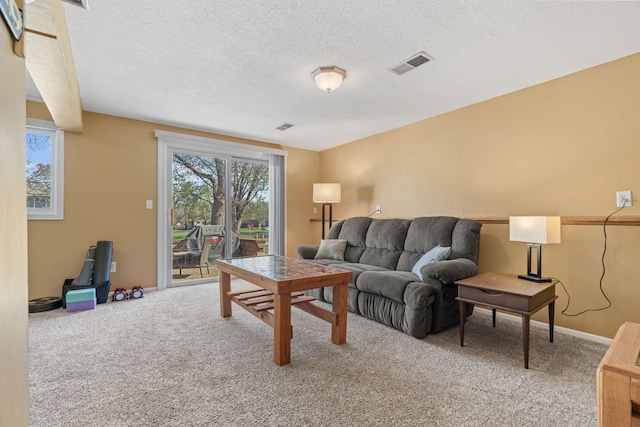 living room with a textured ceiling, carpet flooring, and visible vents