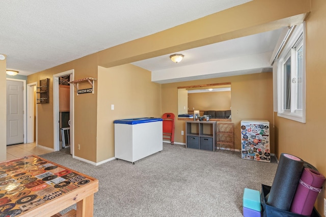 recreation room with light colored carpet, a textured ceiling, and baseboards