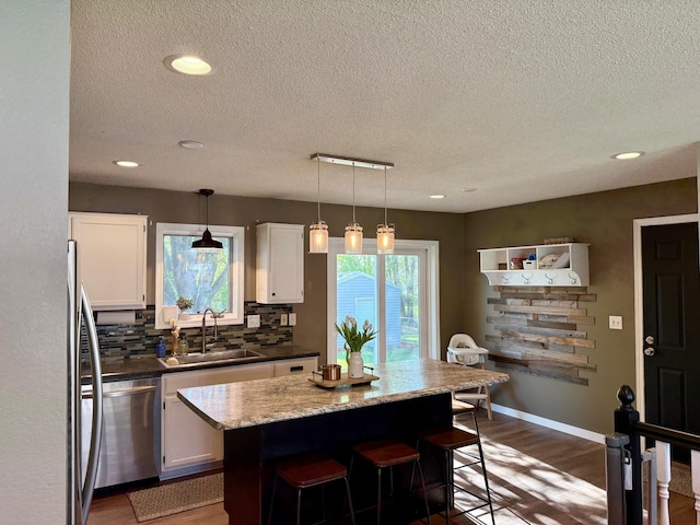 kitchen with dishwasher, a textured ceiling, dark wood-type flooring, and a sink