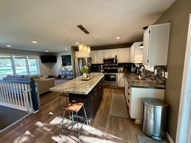 kitchen featuring a sink, dark wood finished floors, white cabinetry, decorative backsplash, and appliances with stainless steel finishes
