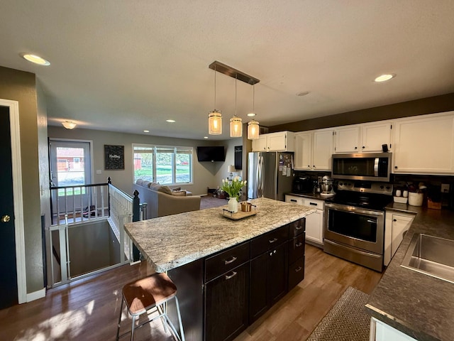 kitchen featuring hanging light fixtures, white cabinets, dark wood-style flooring, appliances with stainless steel finishes, and recessed lighting