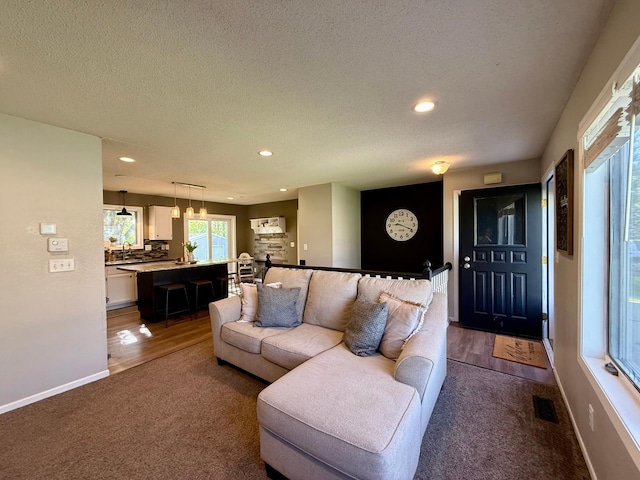 living room featuring recessed lighting, a textured ceiling, baseboards, visible vents, and dark carpet