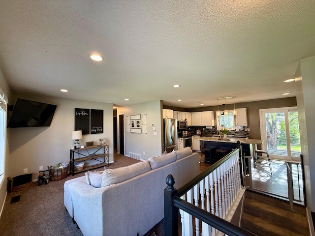 living room with a textured ceiling, visible vents, and recessed lighting