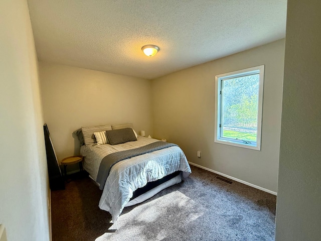 carpeted bedroom with a textured ceiling, baseboards, and visible vents
