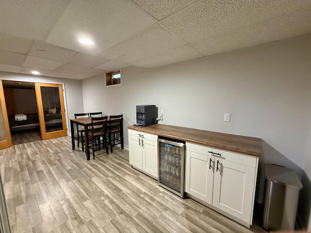 bar featuring wine cooler, a drop ceiling, light wood-style flooring, and recessed lighting
