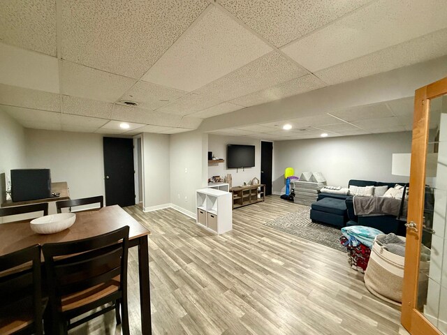 interior space with a paneled ceiling, baseboards, light wood finished floors, and recessed lighting