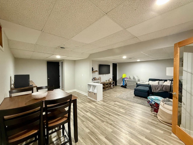 interior space with a paneled ceiling, baseboards, and wood finished floors
