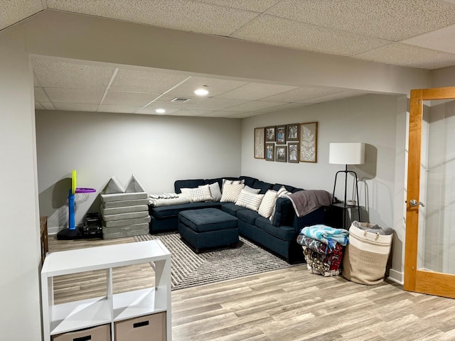 living area with light wood-type flooring, a drop ceiling, baseboards, and recessed lighting