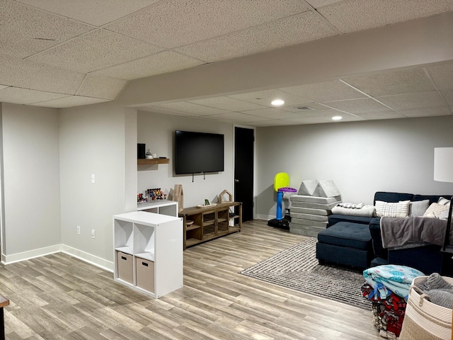 living area featuring a drop ceiling, baseboards, and recessed lighting