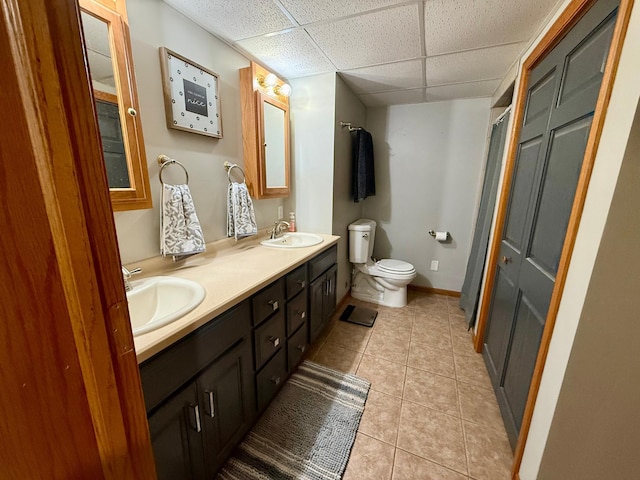 full bathroom with a sink, tile patterned flooring, toilet, and a drop ceiling