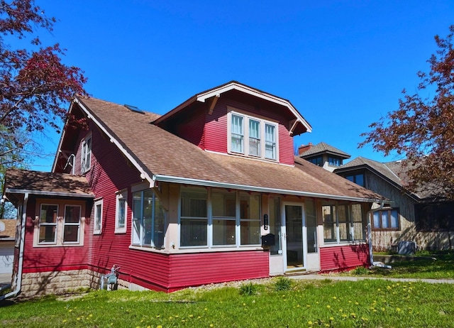 view of front of home featuring a sunroom, a shingled roof, and a front lawn