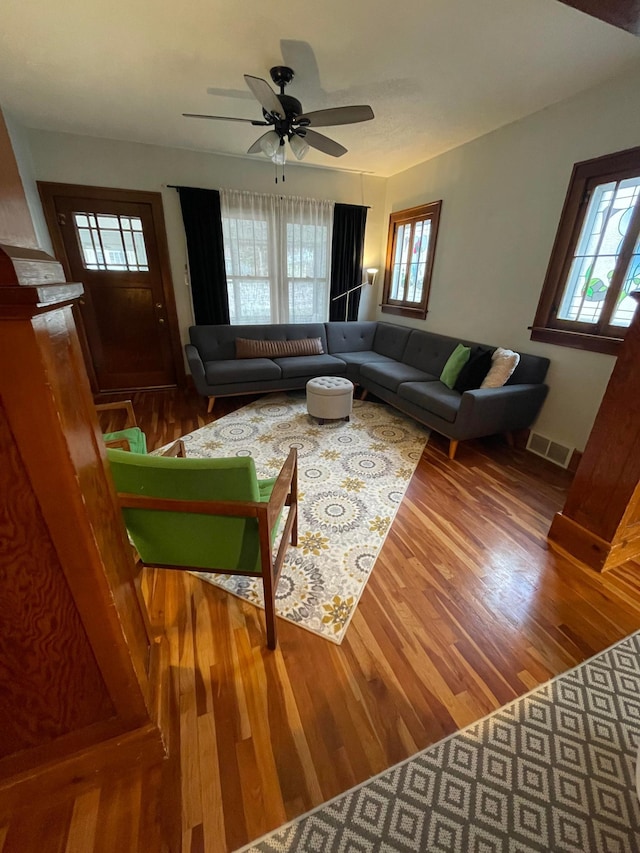 living area with a ceiling fan, visible vents, and wood finished floors
