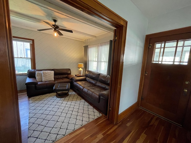 living area featuring wood walls, baseboards, a ceiling fan, and wood finished floors