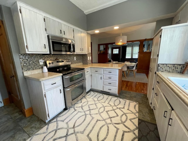 kitchen with a peninsula, light countertops, stainless steel appliances, and tasteful backsplash