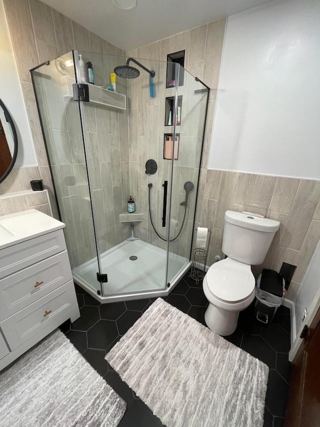 full bathroom featuring toilet, tile patterned floors, tile walls, a shower stall, and vanity