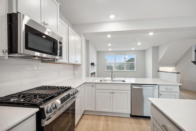 6754 Wildflower Way, Minnetrista, MN 55331 - kitchen featuring appliances with stainless steel finishes, a sink, light wood-style flooring, backsplash, and a peninsula