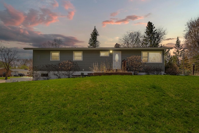 ranch-style home featuring a chimney and a lawn