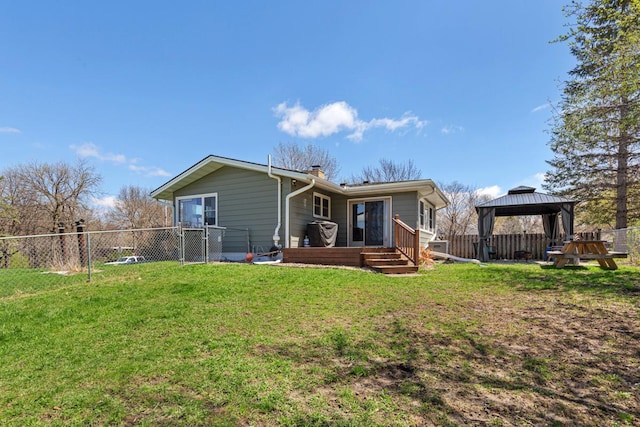 rear view of property featuring a chimney, a gazebo, a lawn, and a fenced backyard
