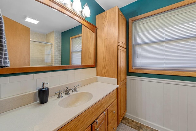 bathroom with vanity, wainscoting, and tiled shower