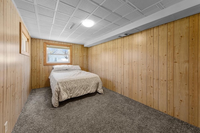 bedroom with wood walls, visible vents, an ornate ceiling, and carpet floors
