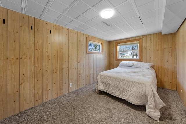 bedroom featuring wooden walls, carpet, and visible vents