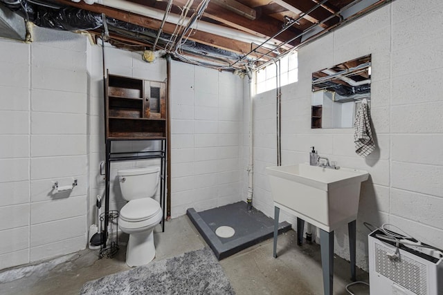 bathroom with unfinished concrete floors, heating unit, a shower stall, and toilet