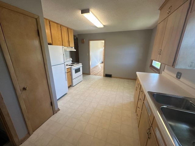 kitchen with white appliances, under cabinet range hood, a sink, a textured ceiling, and light floors