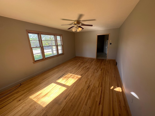 spare room featuring light wood-type flooring, ceiling fan, and baseboards
