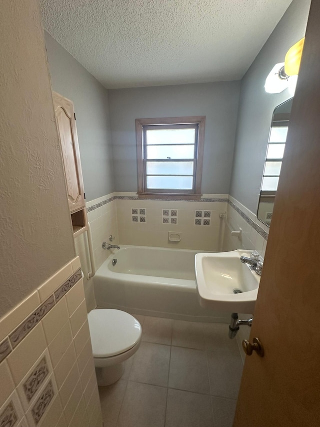 full bathroom featuring tile walls, a sink, a textured ceiling, tile patterned floors, and toilet