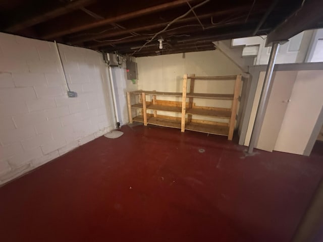 unfinished basement featuring stairway and electric panel