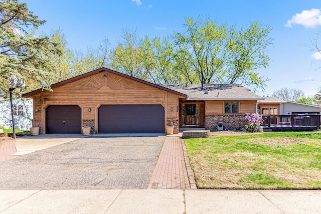 view of front of property with asphalt driveway, brick siding, an attached garage, and a front yard