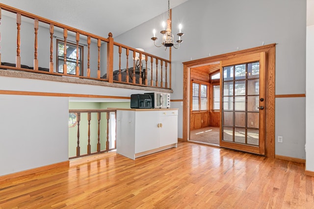 unfurnished room featuring a high ceiling, wood finished floors, a chandelier, and baseboards