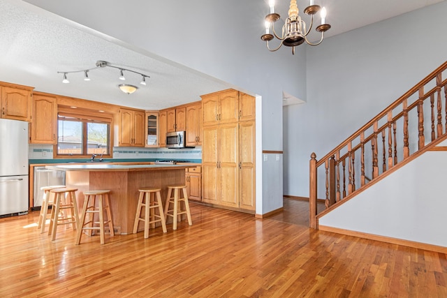 kitchen with stainless steel appliances, light wood-style flooring, a breakfast bar, a center island, and glass insert cabinets