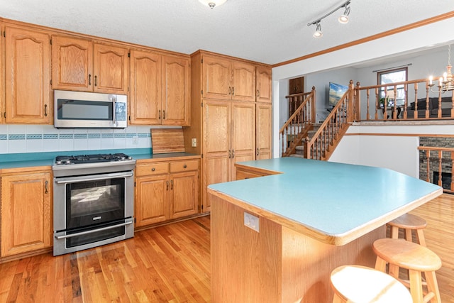 kitchen featuring stainless steel appliances, light wood finished floors, backsplash, a breakfast bar area, and a center island