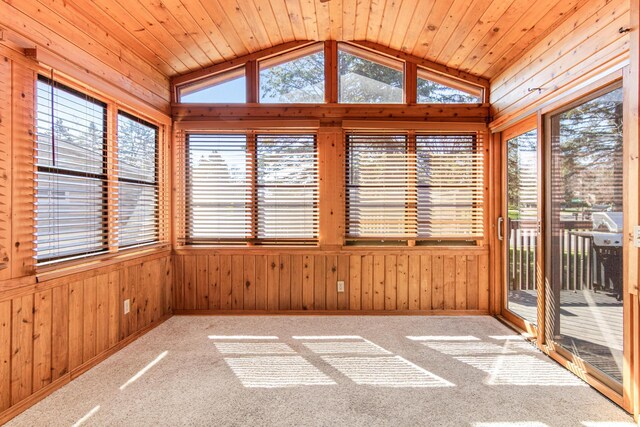unfurnished sunroom with wood walls, lofted ceiling, and carpet