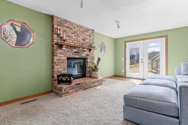 carpeted living room featuring a textured ceiling, a fireplace, baseboards, and french doors