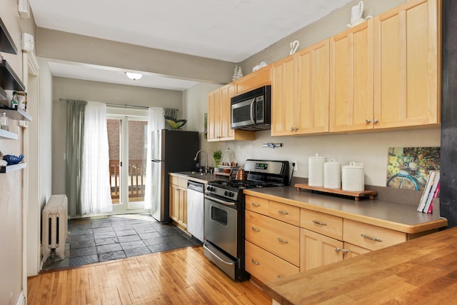 1828 Clinton Ave Unit 3, Minneapolis, MN 55404 - kitchen with stainless steel appliances, light brown cabinetry, and radiator