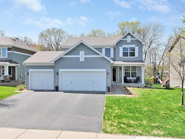traditional-style house with asphalt driveway, an attached garage, a shingled roof, a front yard, and covered porch