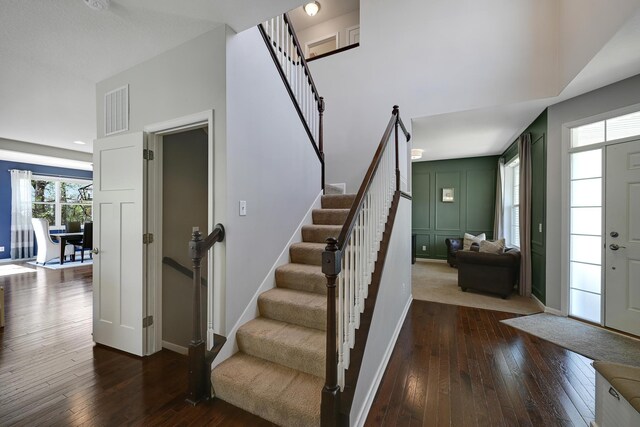 stairs featuring wood-type flooring, baseboards, and a decorative wall