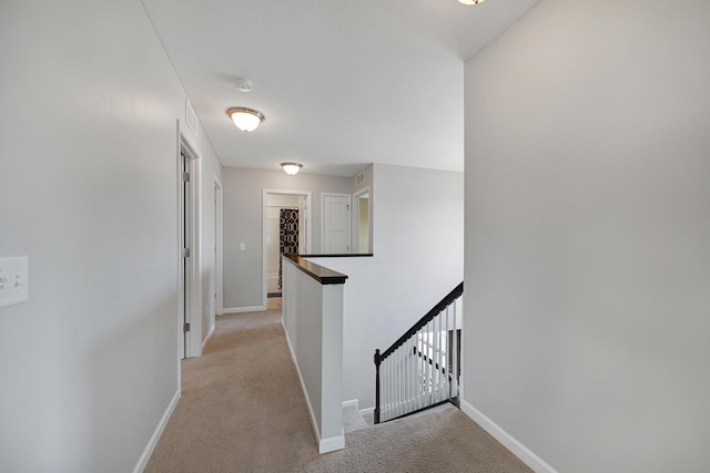 hall featuring an upstairs landing, baseboards, and light carpet