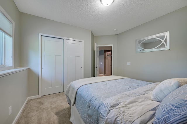 carpeted bedroom featuring a closet, baseboards, and a textured ceiling
