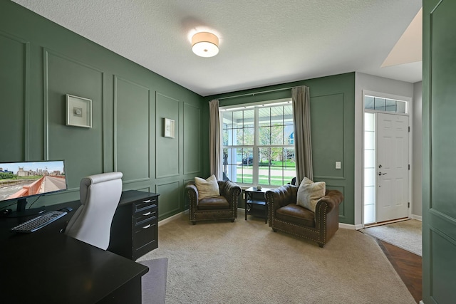 office space featuring a decorative wall, a textured ceiling, and dark carpet