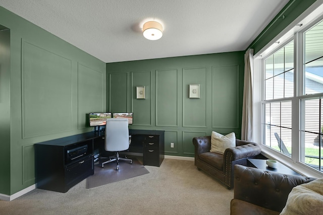 office space with a decorative wall, light colored carpet, and a textured ceiling