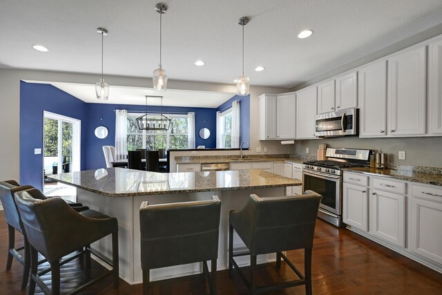 kitchen with appliances with stainless steel finishes, a sink, recessed lighting, a kitchen breakfast bar, and a kitchen island