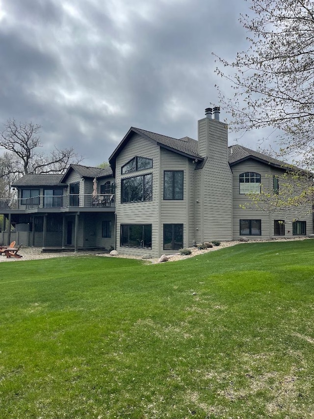 back of house featuring central AC unit, a deck, a chimney, and a lawn
