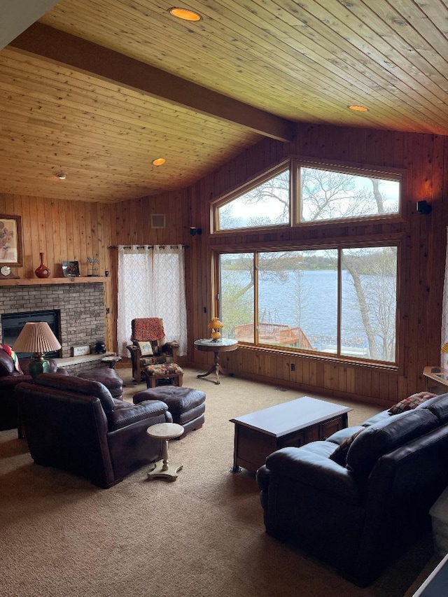 carpeted living room with wood ceiling, wooden walls, a brick fireplace, a water view, and vaulted ceiling with beams