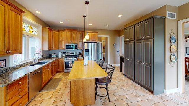 2704 Campus Ln, Albert Lea, MN 56007 - kitchen featuring appliances with stainless steel finishes, a sink, a center island, dark stone countertops, and a breakfast bar area