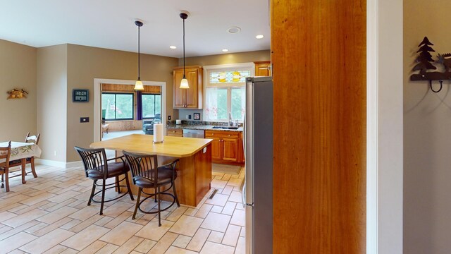 2704 Campus Ln, Albert Lea, MN 56007 - kitchen with appliances with stainless steel finishes, wooden counters, a kitchen breakfast bar, brown cabinets, and a kitchen island