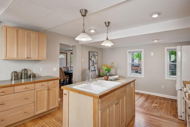 kitchen featuring light brown cabinets, a sink, light wood-style floors, and baseboards