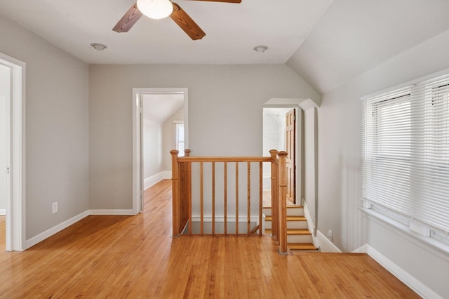 hallway featuring an upstairs landing, healthy amount of natural light, light wood-style flooring, and lofted ceiling